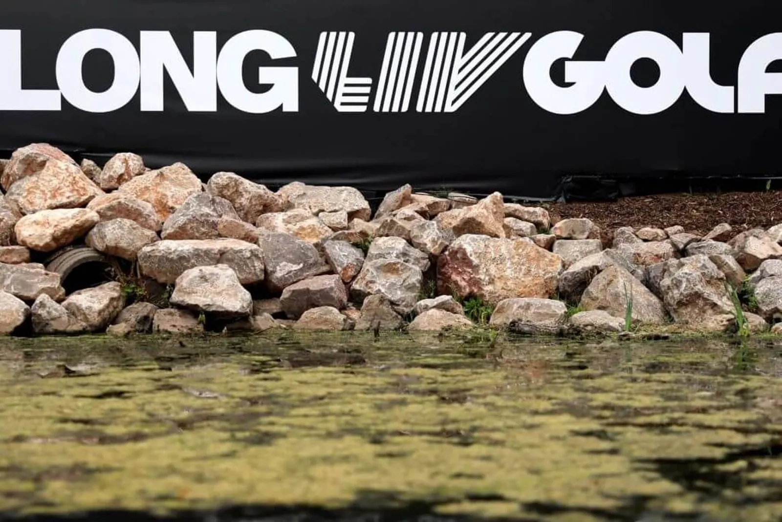 A black "Long LIV Golf" banner with white writing is displayed above a pond surrounded by rocks at the JCB Golf & Country Club on July 23.